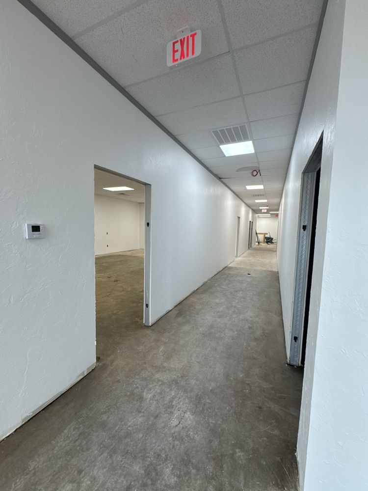 Commercial hallway with bare concrete floor before carpet tile installation